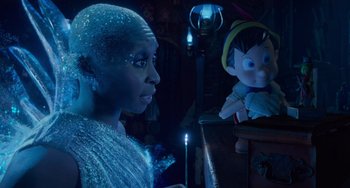 Movie still from “Pinocchio” (2022), directed by Robert Zemeckis – A woman in a blue dress and a stuffed toy; Medium shot, Over the shoulder angle