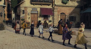 Movie still from “Pinocchio” (2022), directed by Robert Zemeckis – A group of people walking down a street; Extreme Wide shot, High angle