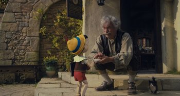 Movie still from “Pinocchio” (2022), directed by Robert Zemeckis – An old man and a young boy are playing with a toy; Wide shot, Low angle