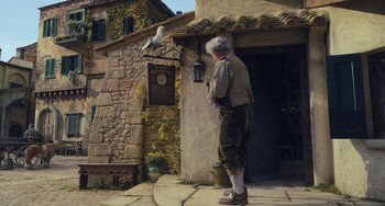 Movie still from “Pinocchio” (2022), directed by Robert Zemeckis – An old man standing next to a stone building; Wide shot, Low angle