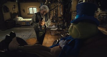 Movie still from “Pinocchio” (2022), directed by Robert Zemeckis – A man standing next to a wooden table; Medium shot, Over the shoulder angle