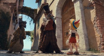 Movie still from “Pinocchio” (2022), directed by Robert Zemeckis – A person standing in front of a building with a person standing next to it; Wide shot, Over the shoulder angle