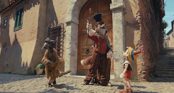 Movie still from “Pinocchio” (2022), directed by Robert Zemeckis – A group of people dressed up like a bunch of racoons standing in front of a door; Wide shot, Low angle