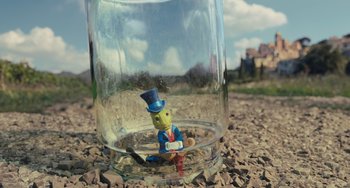 Movie still from “Pinocchio” (2022), directed by Robert Zemeckis – A glass jar with a man in a blue suit sitting in it; Extreme Close Up shot, High angle