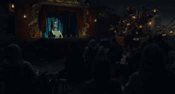 Movie still from “Pinocchio” (2022), directed by Robert Zemeckis – A group of people sitting in front of a stage; Extreme Wide shot, High angle