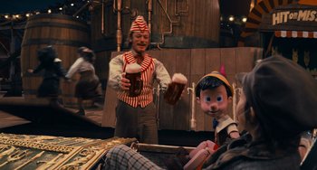 Movie still from “Pinocchio” (2022), directed by Robert Zemeckis – A man in a pinocchio costume is holding a beer; Medium shot, Over the shoulder angle