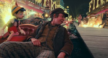 Movie still from “Pinocchio” (2022), directed by Robert Zemeckis – A man sitting on top of a couch in front of a building; Medium shot, High angle