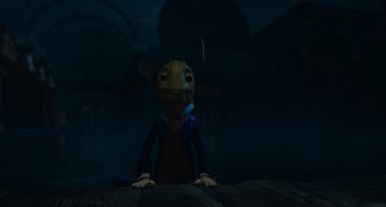 Movie still from “Pinocchio” (2022), directed by Robert Zemeckis – An animated character sitting on top of a wooden table; Medium shot, High angle