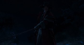 Movie still from “Pinocchio” (2022), directed by Robert Zemeckis – A man in a long coat and a cowboy hat is pulling a rope; Medium shot, Low angle