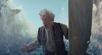 Movie still from “Pinocchio” (2022), directed by Robert Zemeckis – An older man standing next to the ocean; Medium shot, Low angle