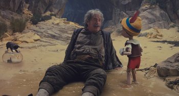 Movie still from “Pinocchio” (2022), directed by Robert Zemeckis – An old man sitting on the ground next to a young boy; Wide shot, High angle