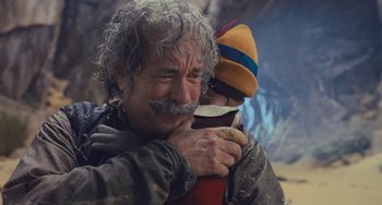 Movie still from “Pinocchio” (2022), directed by Robert Zemeckis – An older man holding a young child in his arms; Close Up shot, Low angle