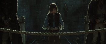 Movie still from “Pirates of the Caribbean: At World's End” (2007), directed by Gore Verbinski – A woman standing next to a rope in a dark room; Medium shot, Low angle