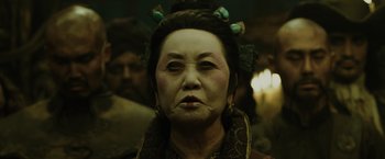 Movie still from “Pirates of the Caribbean: At World's End” (2007), directed by Gore Verbinski – An older woman wearing a headpiece with birds on her head; Close Up shot, Over the shoulder angle