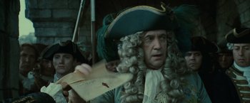 Movie still from “Pirates of the Caribbean: Dead Man's Chest” (2006), directed by Gore Verbinski – A man in a wig and a hat holding a piece of paper in front of him; Close Up shot, Low angle