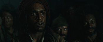Movie still from “Pirates of the Caribbean: Dead Man's Chest” (2006), directed by Gore Verbinski – A man with a beard and a red turban on his head; Close Up shot, Over the shoulder angle