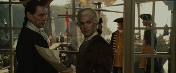 Movie still from “Pirates of the Caribbean: Dead Man's Chest” (2006), directed by Gore Verbinski – A man in a wig standing in front of a boat; Medium shot, Over the shoulder angle