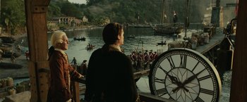 Movie still from “Pirates of the Caribbean: Dead Man's Chest” (2006), directed by Gore Verbinski – A man standing in front of a large clock on a pier; Extreme Wide shot, Over the shoulder angle