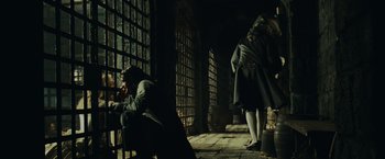 Movie still from “Pirates of the Caribbean: Dead Man's Chest” (2006), directed by Gore Verbinski – A man sitting in a dark room next to a woman; Wide shot, Over the shoulder angle