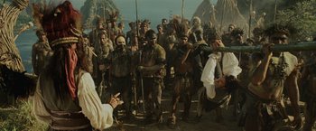 Movie still from “Pirates of the Caribbean: Dead Man's Chest” (2006), directed by Gore Verbinski – A group of people in costumes and a man in a white robe; Wide shot, Over the shoulder angle