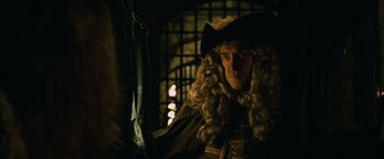 Movie still from “Pirates of the Caribbean: Dead Man's Chest” (2006), directed by Gore Verbinski – A man wearing a wig and a wig stand in front of a cage; Medium shot, Over the shoulder angle
