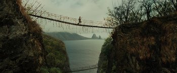 Movie still from “Pirates of the Caribbean: Dead Man's Chest” (2006), directed by Gore Verbinski – A person walking across a bridge over a body of water; Extreme Wide shot, High angle
