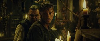 Movie still from “Pirates of the Caribbean: Dead Man's Chest” (2006), directed by Gore Verbinski – A man standing in front of a group of candles; Close Up shot, Over the shoulder angle