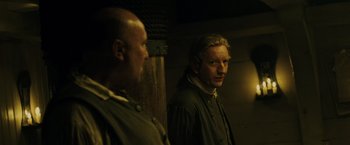 Movie still from “Pirates of the Caribbean: Dead Man's Chest” (2006), directed by Gore Verbinski – Two men are looking at each other in a dimly - lit room; Medium shot, Over the shoulder angle