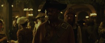 Movie still from “Pirates of the Caribbean: Dead Man's Chest” (2006), directed by Gore Verbinski – A man wearing a pirate hat standing next to other men; Medium shot, Over the shoulder angle