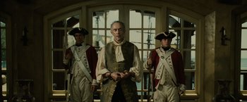 Movie still from “Pirates of the Caribbean: Dead Man's Chest” (2006), directed by Gore Verbinski – A group of men standing next to each other in front of a window; Medium shot, Low angle