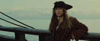 Movie still from “Pirates of the Caribbean: Dead Man's Chest” (2006), directed by Gore Verbinski – A woman in a pirate costume standing next to a boat; Close Up shot, Low angle