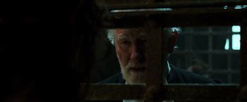 Movie still from “Pirates of the Caribbean: Dead Men Tell No Tales” (2017), directed by Espen Sandberg – An older man looking out a window at night; Close Up shot, Over the shoulder angle