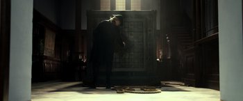 Movie still from “Pirates of the Caribbean: Dead Men Tell No Tales” (2017), directed by Espen Sandberg – A man in a black suit is looking into a large metal box; Wide shot, Low angle