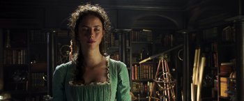 Movie still from “Pirates of the Caribbean: Dead Men Tell No Tales” (2017), directed by Espen Sandberg – A woman in a green dress in front of a bookshelf; Close Up shot, Low angle