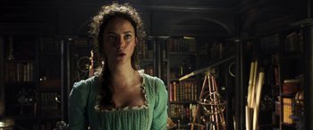 Movie still from “Pirates of the Caribbean: Dead Men Tell No Tales” (2017), directed by Espen Sandberg – A woman standing in front of a bookshelf in a room; Close Up shot, Over the shoulder angle