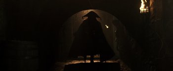 Movie still from “Pirates of the Caribbean: Dead Men Tell No Tales” (2017), directed by Espen Sandberg – A person in a hat standing in the dark under an arch; Wide shot, Low angle