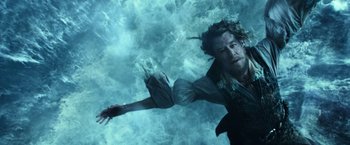 Movie still from “Pirates of the Caribbean: Dead Men Tell No Tales” (2017), directed by Espen Sandberg – A man is swimming in the water with his arms outstretched; Medium shot, Overhead angle