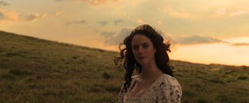 Movie still from “Pirates of the Caribbean: Dead Men Tell No Tales” (2017), directed by Espen Sandberg – A woman standing in a grassy field at sunset; Close Up shot, Low angle