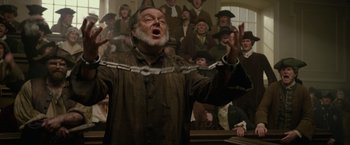 Movie still from “Pirates of the Caribbean: On Stranger Tides” (2011), directed by Rob Marshall – An old man is chained up in front of a group of people; Medium shot, Low angle