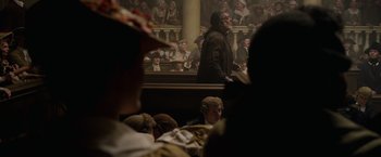 Movie still from “Pirates of the Caribbean: On Stranger Tides” (2011), directed by Rob Marshall – A crowd of people sitting and standing in front of a building; Medium shot, Over the shoulder angle