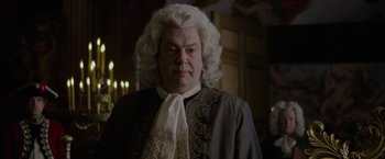 Movie still from “Pirates of the Caribbean: On Stranger Tides” (2011), directed by Rob Marshall – A man in a wig and wig stands in front of candles; Close Up shot, Over the shoulder angle