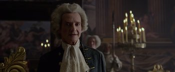 An old man in a wig and wig stands in front of other men