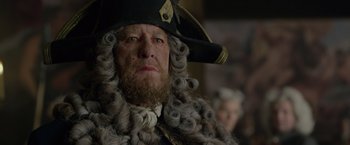 Movie still from “Pirates of the Caribbean: On Stranger Tides” (2011), directed by Rob Marshall – A man with a beard wearing a pirate hat and wig; Close Up shot, Over the shoulder angle