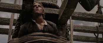 Movie still from “Pirates of the Caribbean: On Stranger Tides” (2011), directed by Rob Marshall – A young man is tied to a wooden structure; Close Up shot, Overhead angle