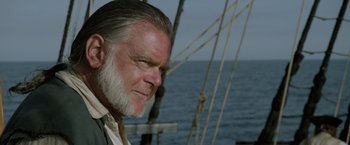 Movie still from “Pirates of the Caribbean: On Stranger Tides” (2011), directed by Rob Marshall – An older man with a beard is on a boat in the ocean; Close Up shot, Over the shoulder angle