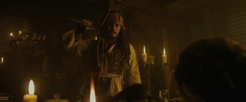 Movie still from “Pirates of the Caribbean: On Stranger Tides” (2011), directed by Rob Marshall – A man in a pirate costume holding a sword in front of candles; Medium shot, Over the shoulder angle