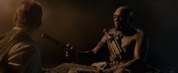 Movie still from “Pirates of the Caribbean: On Stranger Tides” (2011), directed by Rob Marshall – A man sitting on the ground holding a gun; Medium shot, High angle