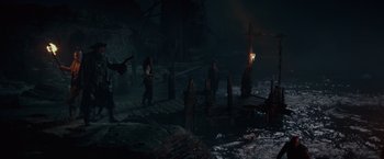 Movie still from “Pirates of the Caribbean: On Stranger Tides” (2011), directed by Rob Marshall – A group of people standing on top of a wooden dock at night; Wide shot, High angle