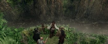 Movie still from “Pirates of the Caribbean: On Stranger Tides” (2011), directed by Rob Marshall – A group of people standing in the grass near a body of water; Extreme Wide shot, Overhead angle