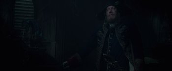 Movie still from “Pirates of the Caribbean: On Stranger Tides” (2011), directed by Rob Marshall – A man dressed as a pirate holding a red book; Medium shot, Low angle